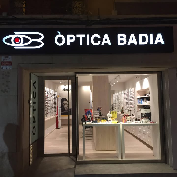 Façana d'Òptica Badia al carrer dels Ferrers, amb el rètol il·luminat de nit